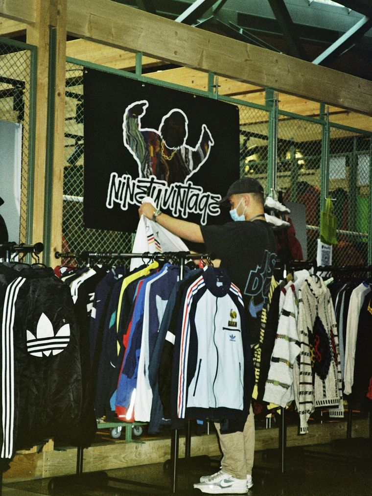 The ninetyvintage stand at a vintage fair: a rail of 90s track jackets under the shop banner.
