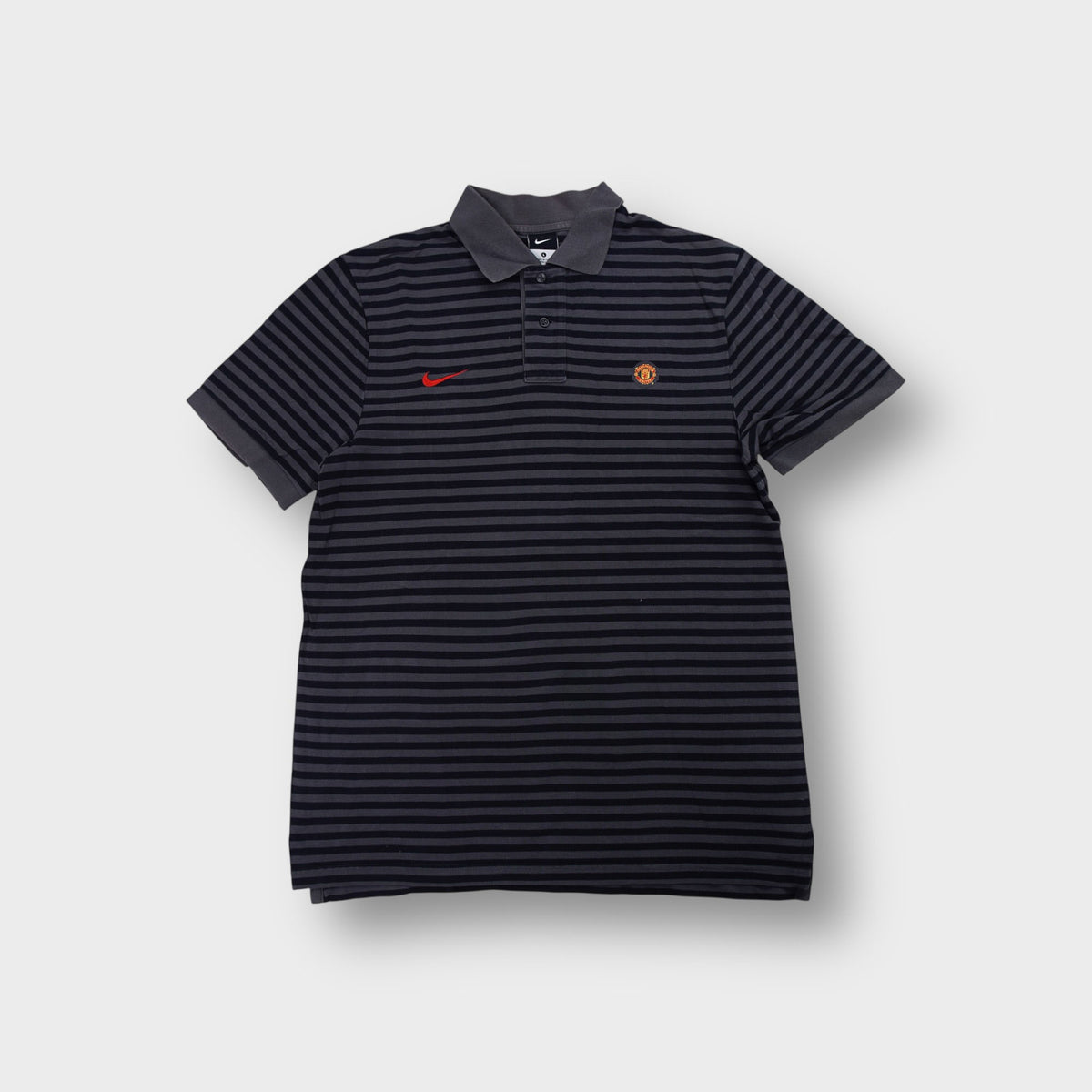 Nike Manchester United polo shirt in black and grey stripes with red swoosh logo
