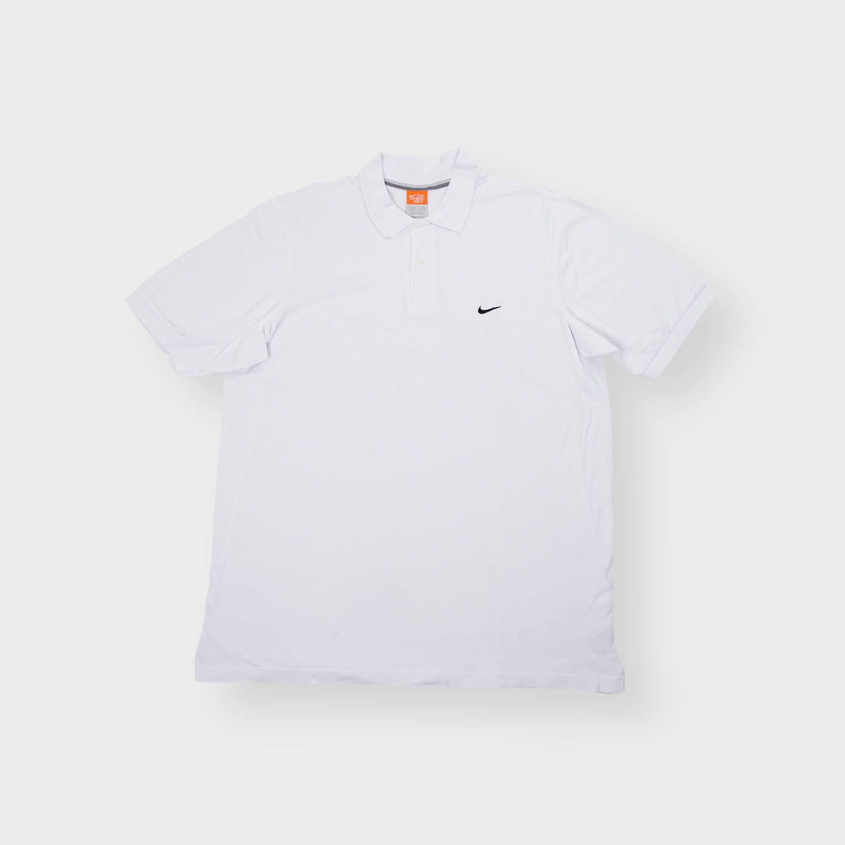 Nike short sleeve polo shirt in white featuring a small black swoosh logo embroidered on the chest