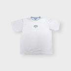 Nike T-Shirt in white featuring blue embroidered central text and swoosh chest logo.