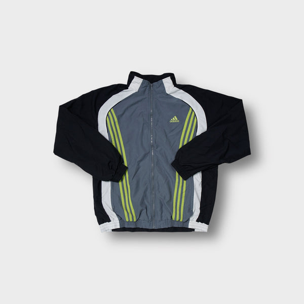 Adidas track jacket in grey and black with yellow three-stripe chest embroidery.