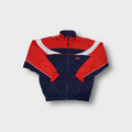 Adidas track jacket in navy, red, and white featuring geometric paneling and white piping.