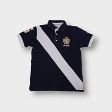 Lade das Bild in den Galerie-Viewer, Solera polo shirt in navy featuring a white diagonal sash and embroidered chest crest