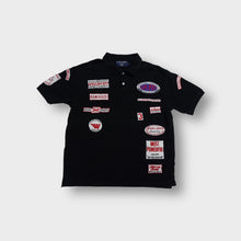 Load image into Gallery viewer, Black Scapa Sports polo shirt featuring multiple red and white embroidered patches