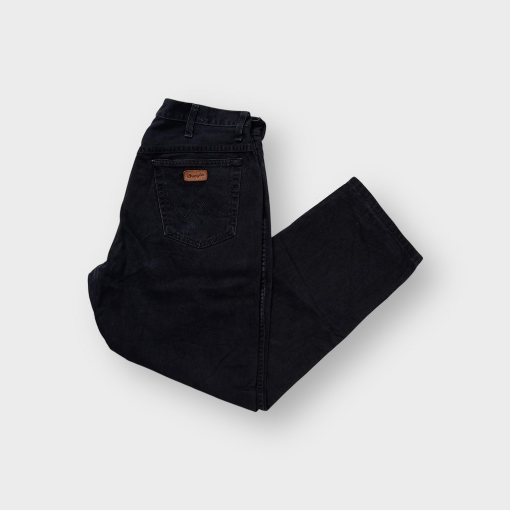 Black Wrangler denim jeans with a brown leather logo patch on the back pocket