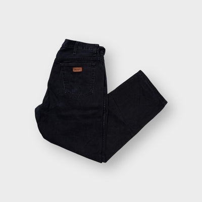 Black Wrangler denim jeans with a brown leather logo patch on the back pocket