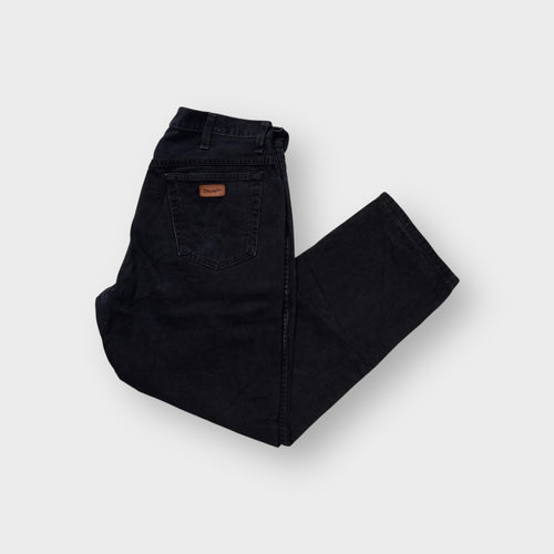 Black Wrangler denim jeans with a brown leather logo patch on the back pocket