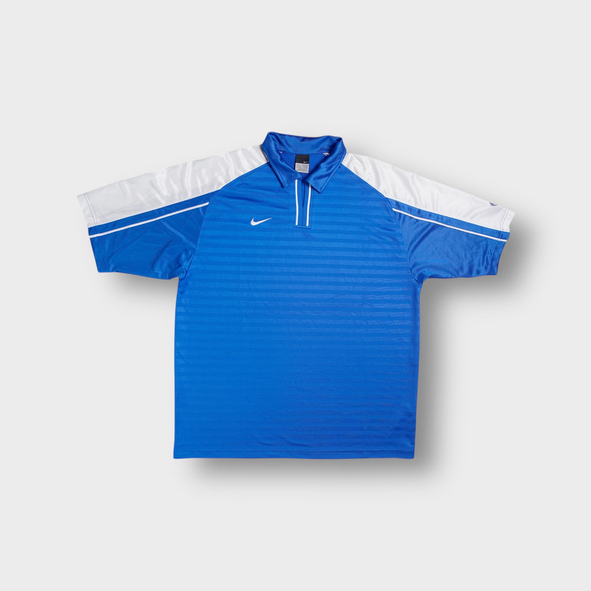 Blue Nike polo shirt with white shoulder panels and small embroidered white Swoosh