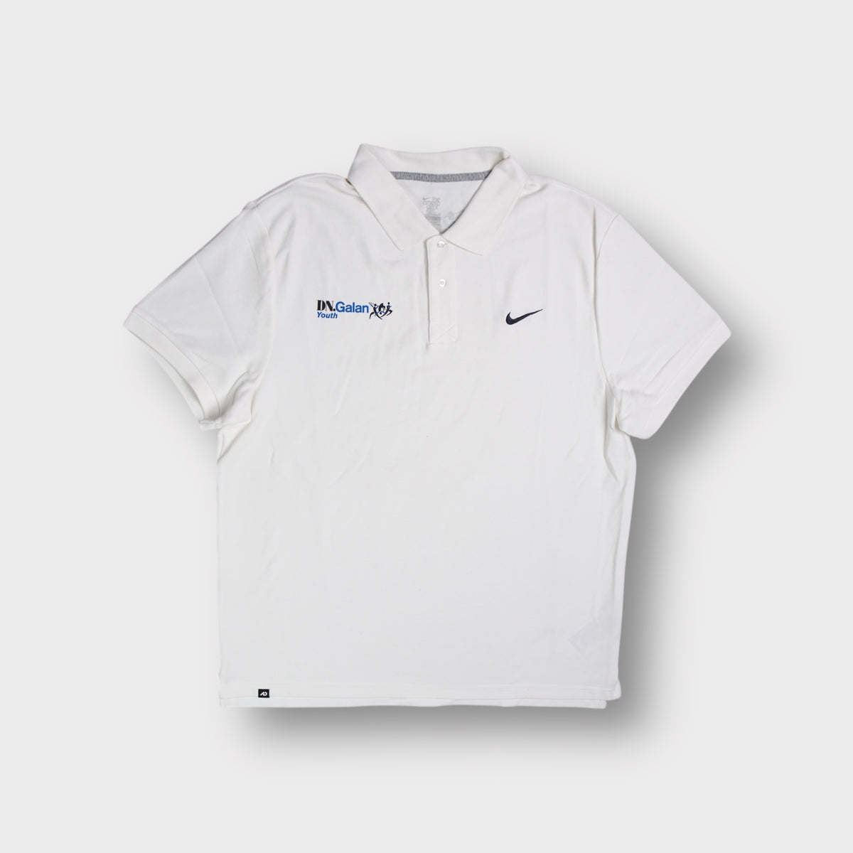 White Nike polo shirt with DN.Galan Youth embroidery and small black swoosh logo.