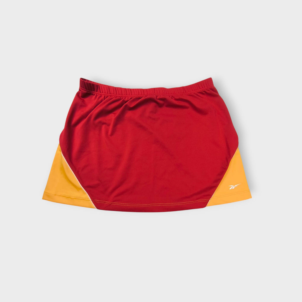 Reebok athletic skirt in red and yellow with printed white vector logo at hem.