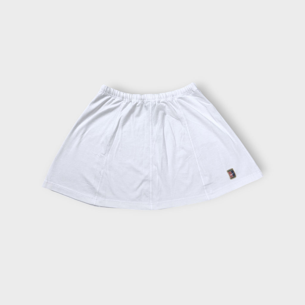 Nike mini tennis skirt in white with a colorful embroidered court logo patch near hem