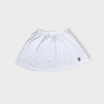 Nike mini tennis skirt in white with a colorful embroidered court logo patch near hem