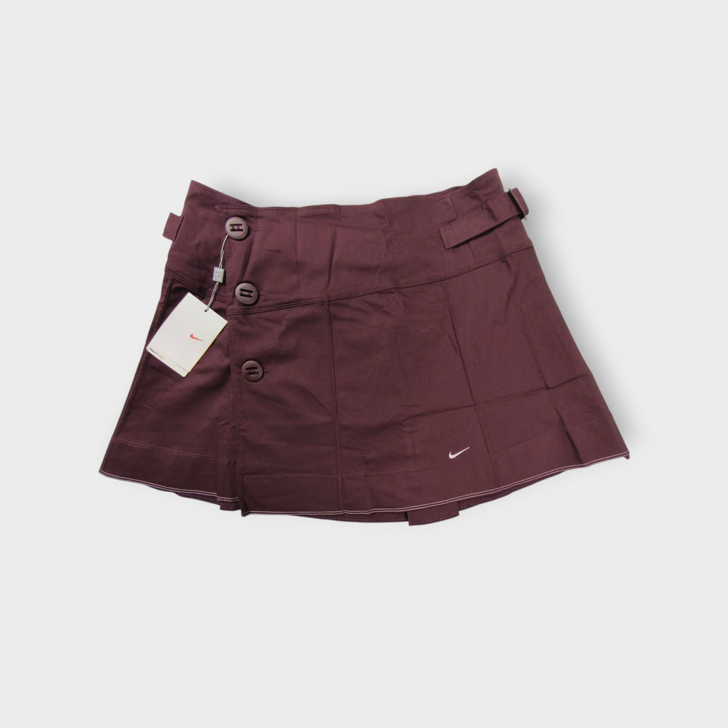 Nike women's tennis skirt in dark red with side button closures and waist buckles.