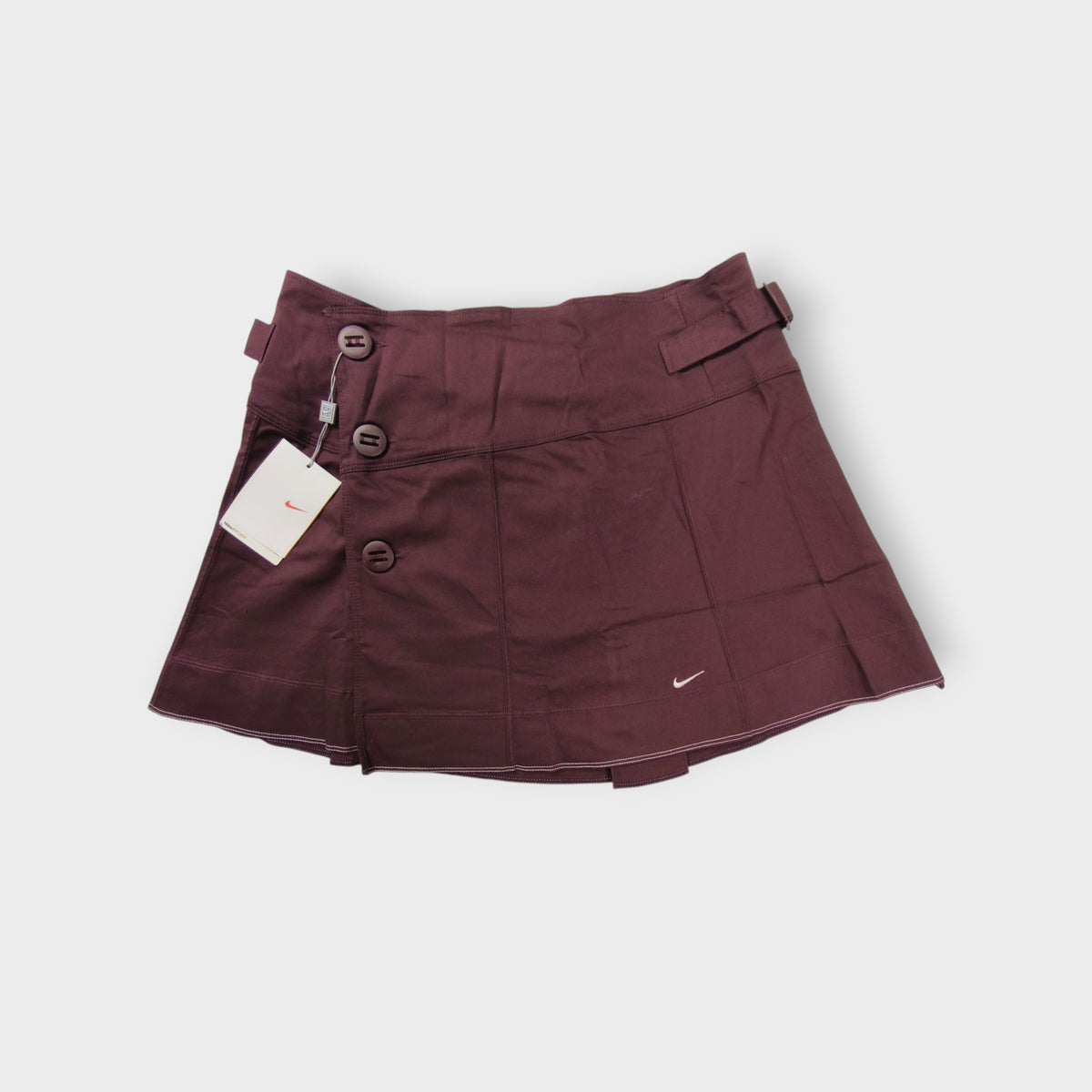 Nike women's tennis skirt in dark red with side button closures and waist buckles.