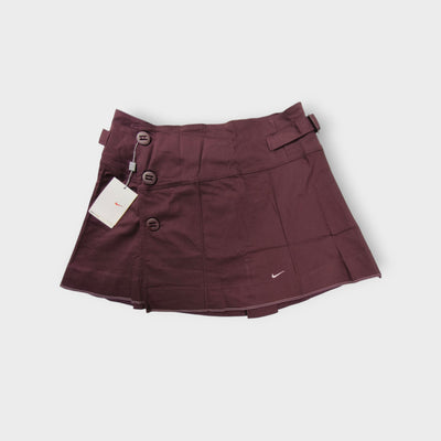 Nike women's tennis skirt in dark red with side button closures and waist buckles.