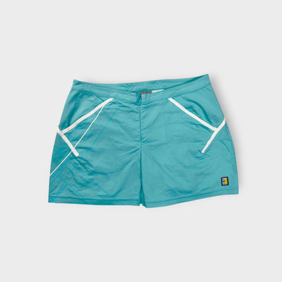 Nike turquoise tennis skirt featuring white trim and a small court patch at the hem.