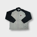 Nike track jacket in grey and black with a red shield logo patch on the chest