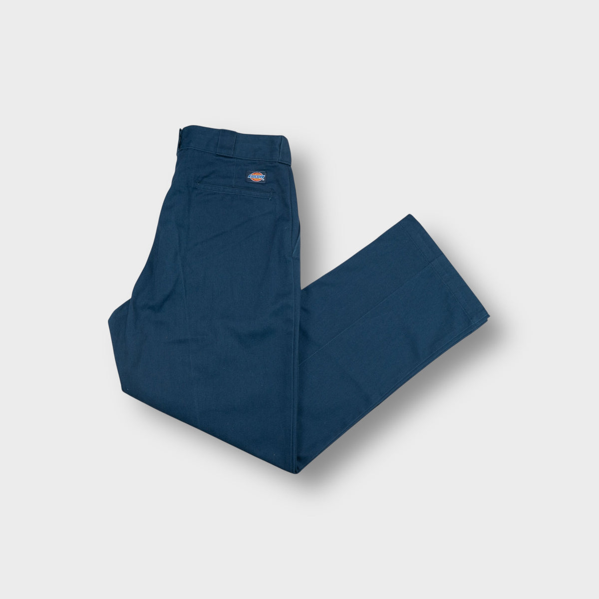 Blue Dickies work pants with a woven brand patch above the rear welt pocket