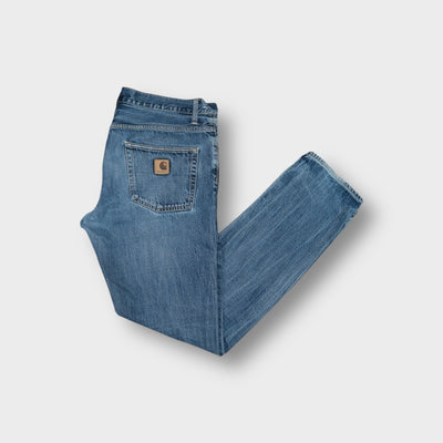 Carhartt blue denim jeans featuring a leather logo patch on the back pocket
