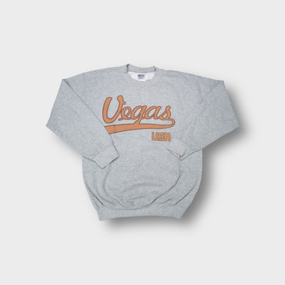 Gildan crew-neck sweater in grey featuring brown script Vegas USA lettering across the chest