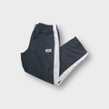 Umbro trackpants in dark grey featuring side stripes and an embroidered logo patch