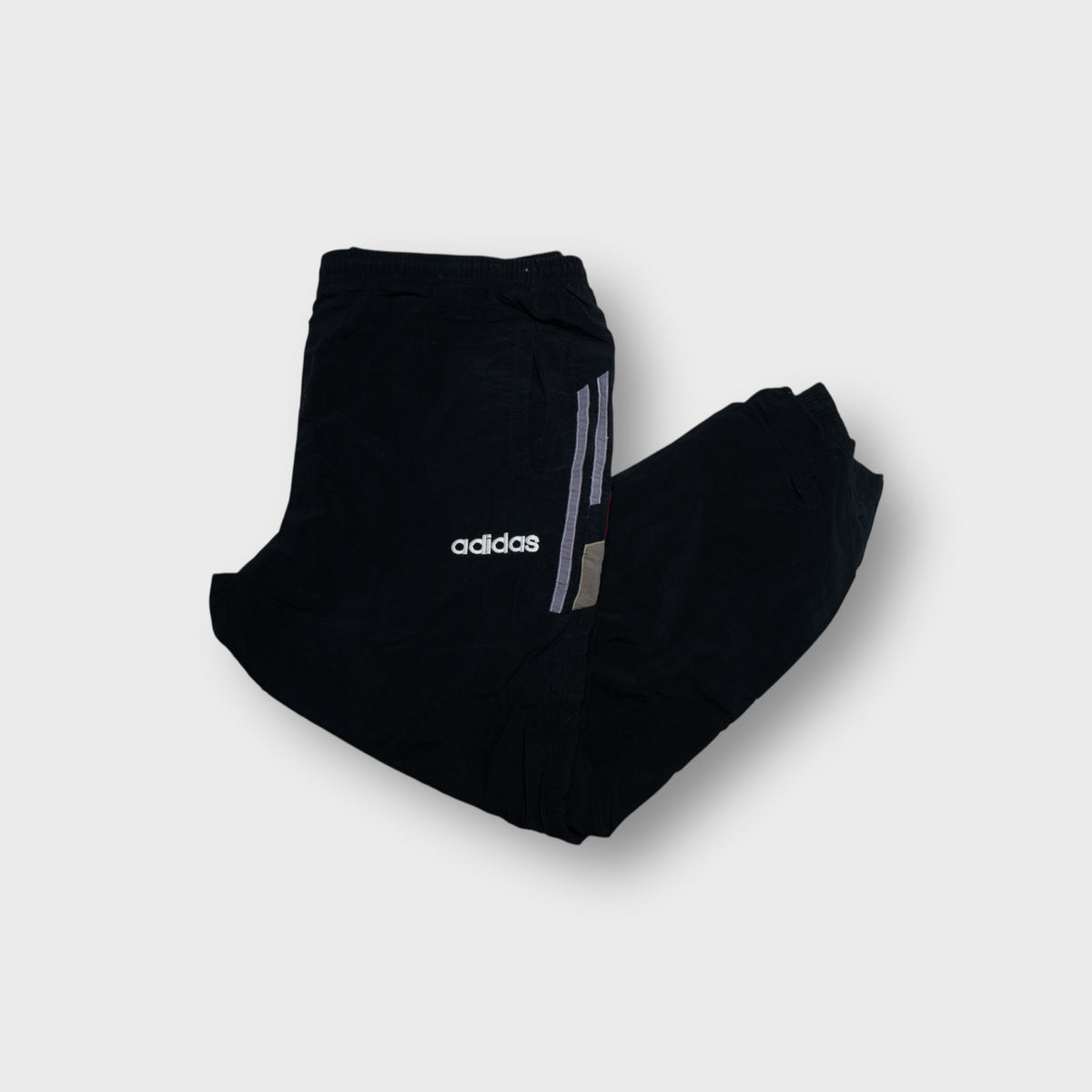 Adidas trackpants in black with embroidered white text logo and red side accent panels