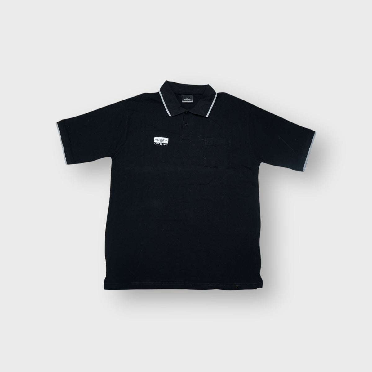 Umbro polo shirt in black featuring an embroidered chest logo patch and grey tipped collar