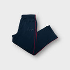 Navy blue Nike track pants with red side piping and small white embroidered swoosh