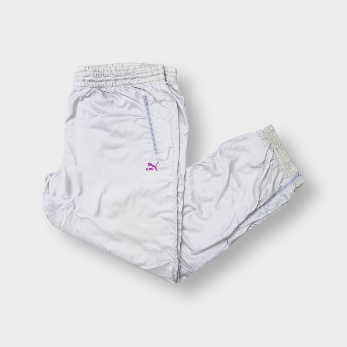 Puma trackpants in light grey with a purple embroidered logo and zipped pockets