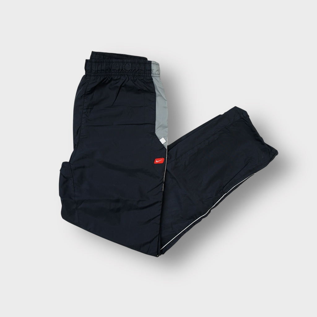 Nike black trackpants with a red swoosh patch on the upper pocket.