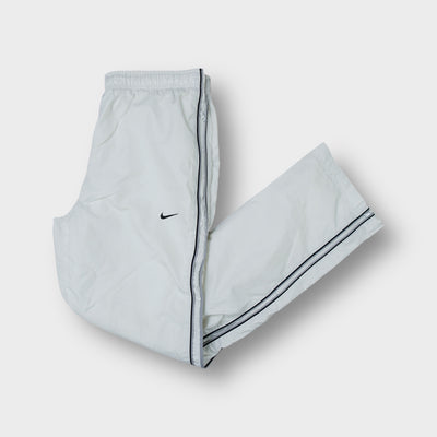 White Nike trackpants featuring dark side piping and embroidered Swoosh logo