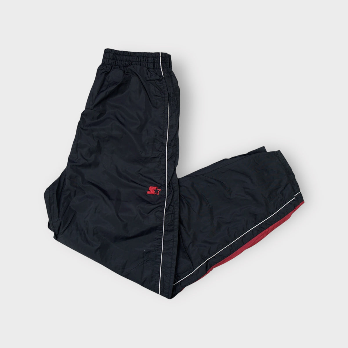 Starter black trackpants with white side piping and a small red embroidered logo near the waist.
