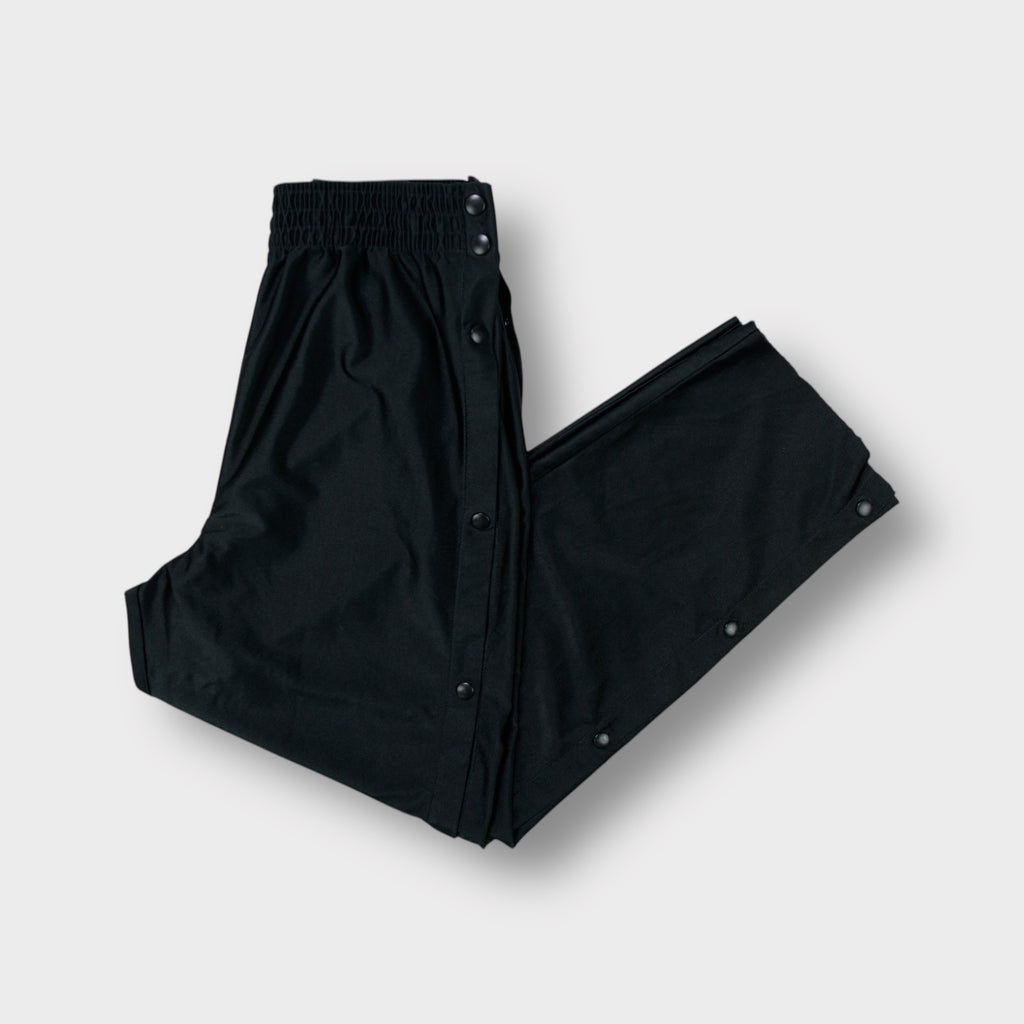 Black Nike tearaway trackpants featuring side snap buttons and an embroidered Swoosh