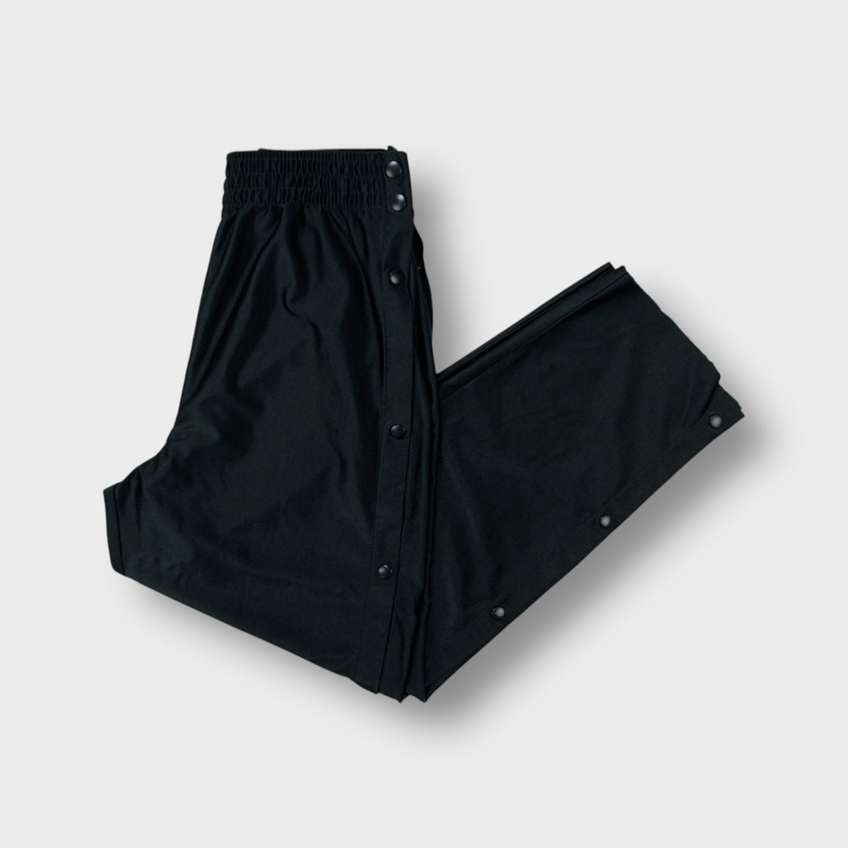 Black Nike tearaway trackpants featuring side snap buttons and an embroidered Swoosh