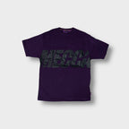 Mecca T-Shirt in purple featuring a large black logo printed across the chest