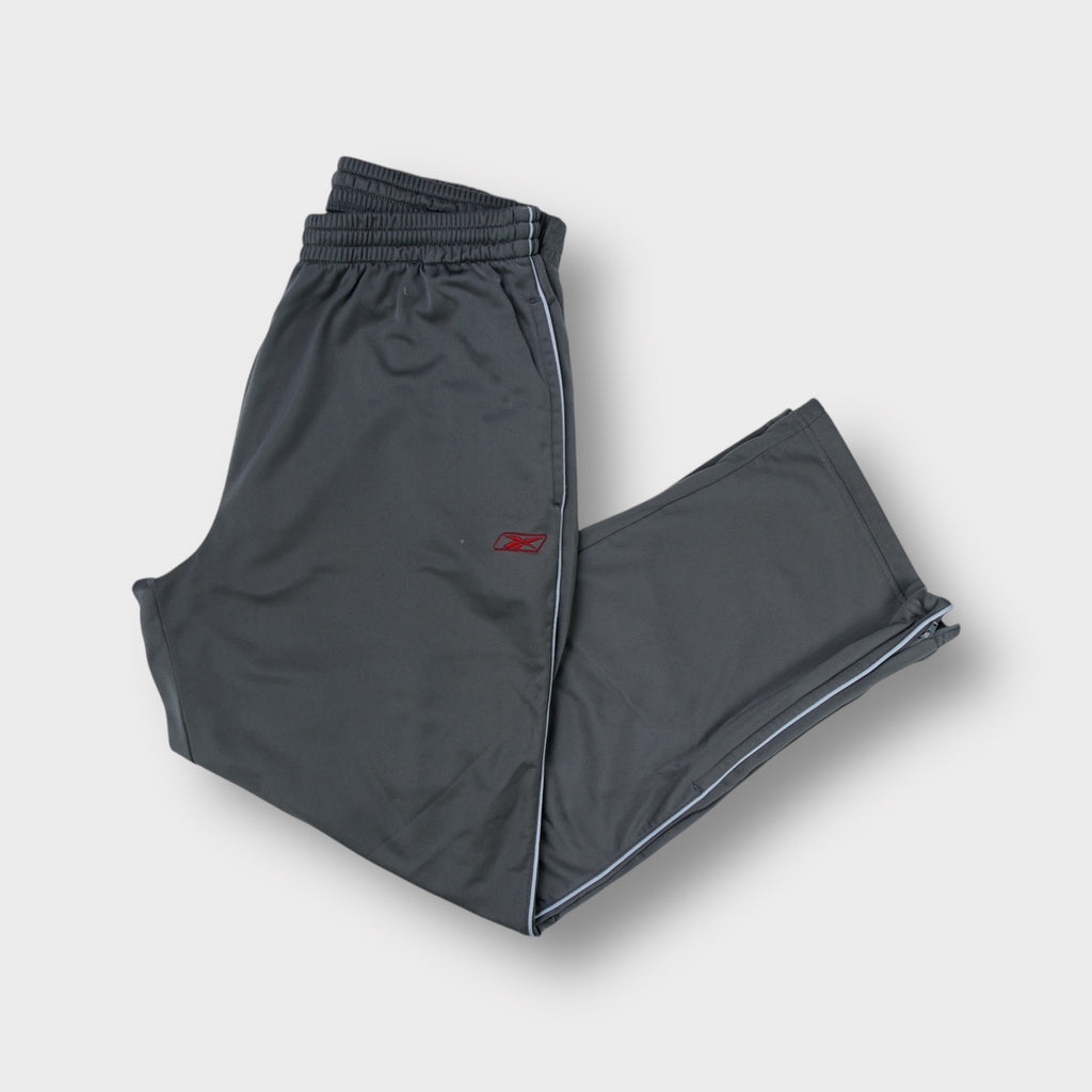 Reebok grey trackpants featuring a red embroidered vector logo on the leg and white side piping.