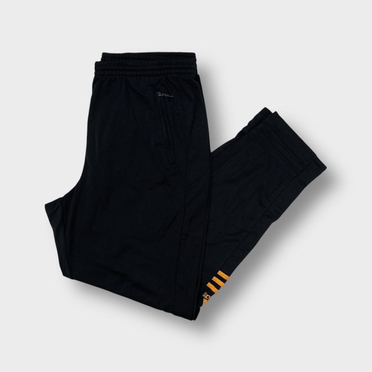 Black Adidas trackpants with gold lower-leg stripes and embroidered logos