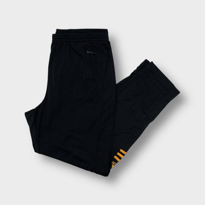 Black Adidas trackpants with gold lower-leg stripes and embroidered logos