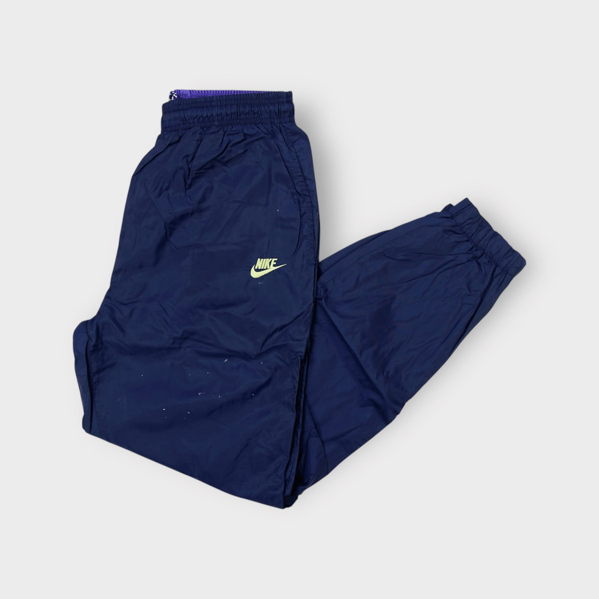 Nike trackpants in blue featuring a neon embroidered logo near the waist