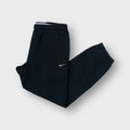 Nike black sweatpants with a small embroidered white swoosh logo on the side hip.