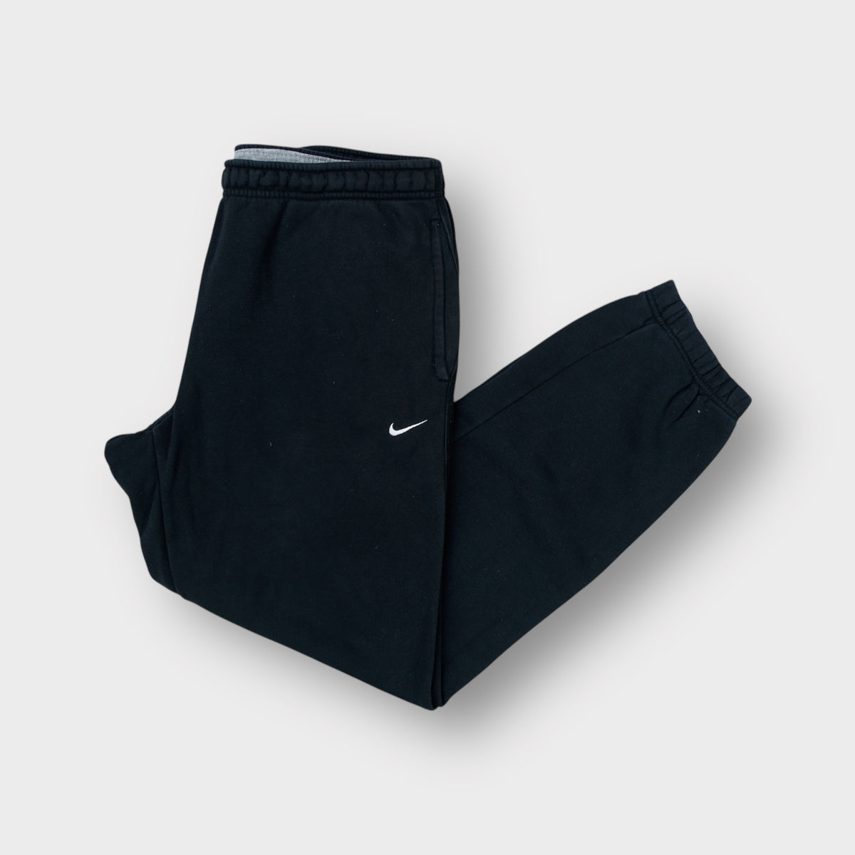 Nike black sweatpants with a small embroidered white swoosh logo on the side hip.