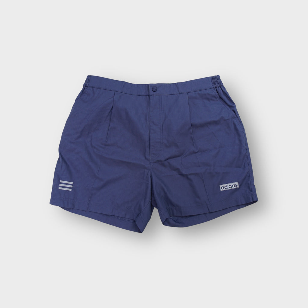 Blue Adidas shorts with a small rectangular logo patch and pleated front construction