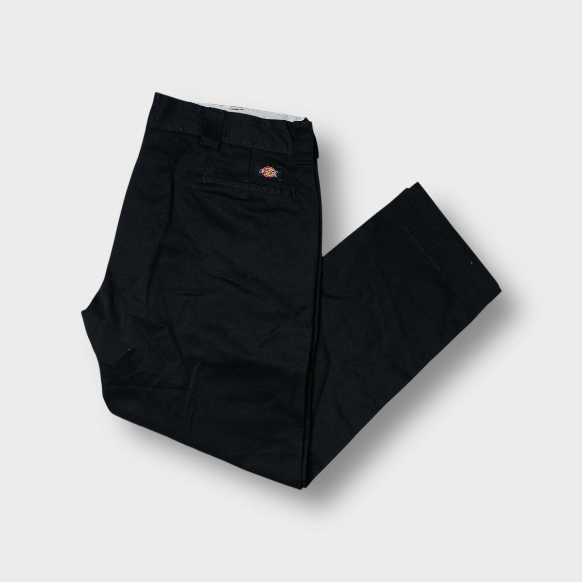 Black Dickies work trousers with a red woven logo patch above the back welt pocket
