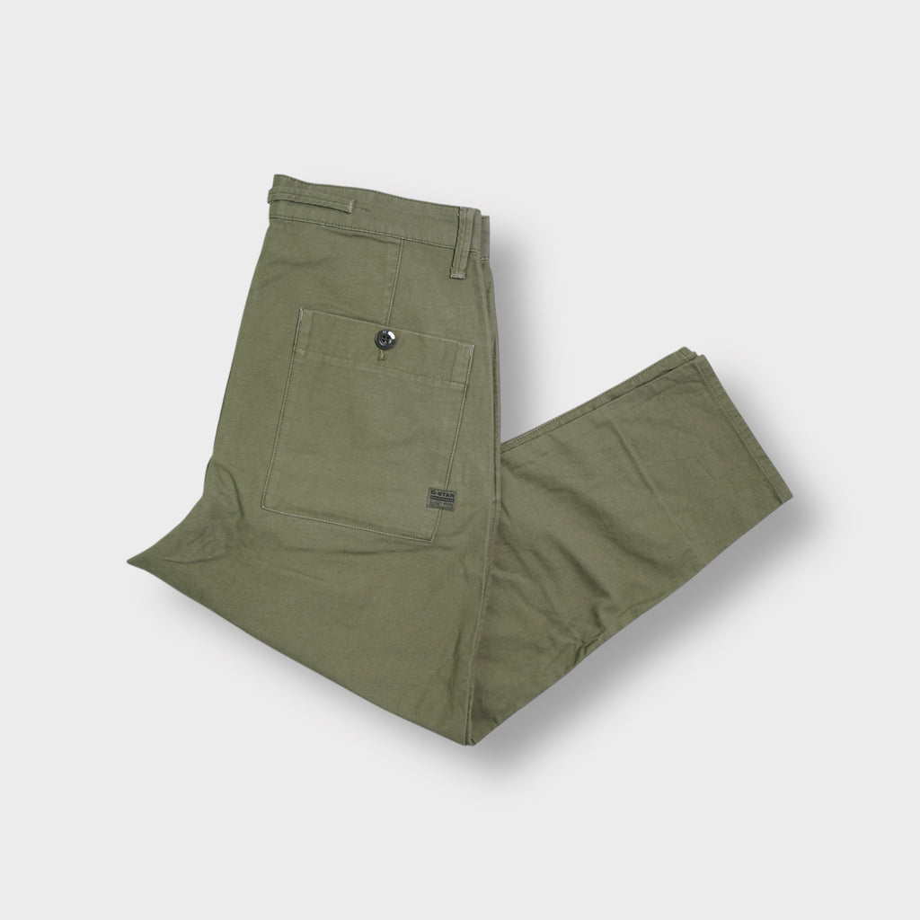 G-Star khaki pants laid flat featuring a small metal logo plaque at the waist pocket