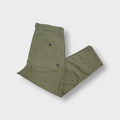 G-Star khaki pants laid flat featuring a small metal logo plaque at the waist pocket