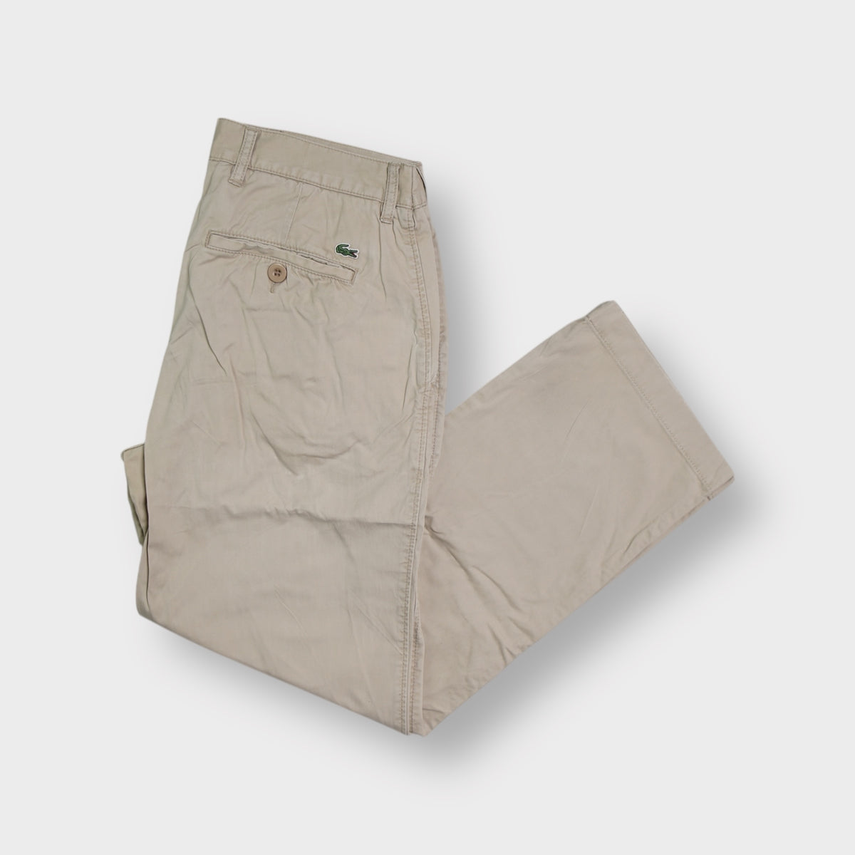Lacoste beige trousers featuring an embroidered green crocodile logo on the back pocket