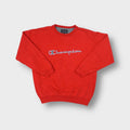 Red Champion crew neck sweater with a large embroidered brand logo on the chest.