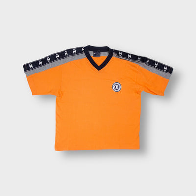 Champion orange V-neck T-Shirt featuring logo shoulder tape and circular chest graphic.