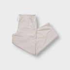 Nike beige trackpants showing an embroidered white swoosh logo near the side pocket
