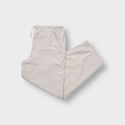 Nike beige trackpants showing an embroidered white swoosh logo near the side pocket